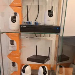 Ekspozycja kamer IP Imou Ranger 2 i rejestratora w szklanej gablocie, widoczne pudełka i akcesoria montażowe.