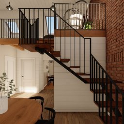 MG Interior Art Marta Godun - Wnętrze domu z ceglaną ścianą, schodami z czarną balustradą, antresolą i widoczną przestrzenią jadalną z drewnianym stołem i czarnymi krzesłami, w tle kominek.
