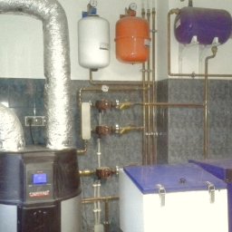 PB-TECH Piotr Borkowski - Instalacja grzewcza z kotłem, rurami miedzianymi i zbiornikami wyrównawczymi w pomieszczeniu z wykończeniem ceramicznym.