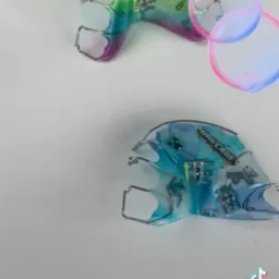 Dwa aparaty ortodontyczne na białym tle, jeden z motywem Roblox Minecraft w odcieniach różu i zieleni, drugi z motywem Minecraft w odcieniach niebieskiego. Widoczne metalowe elementy mocujące.