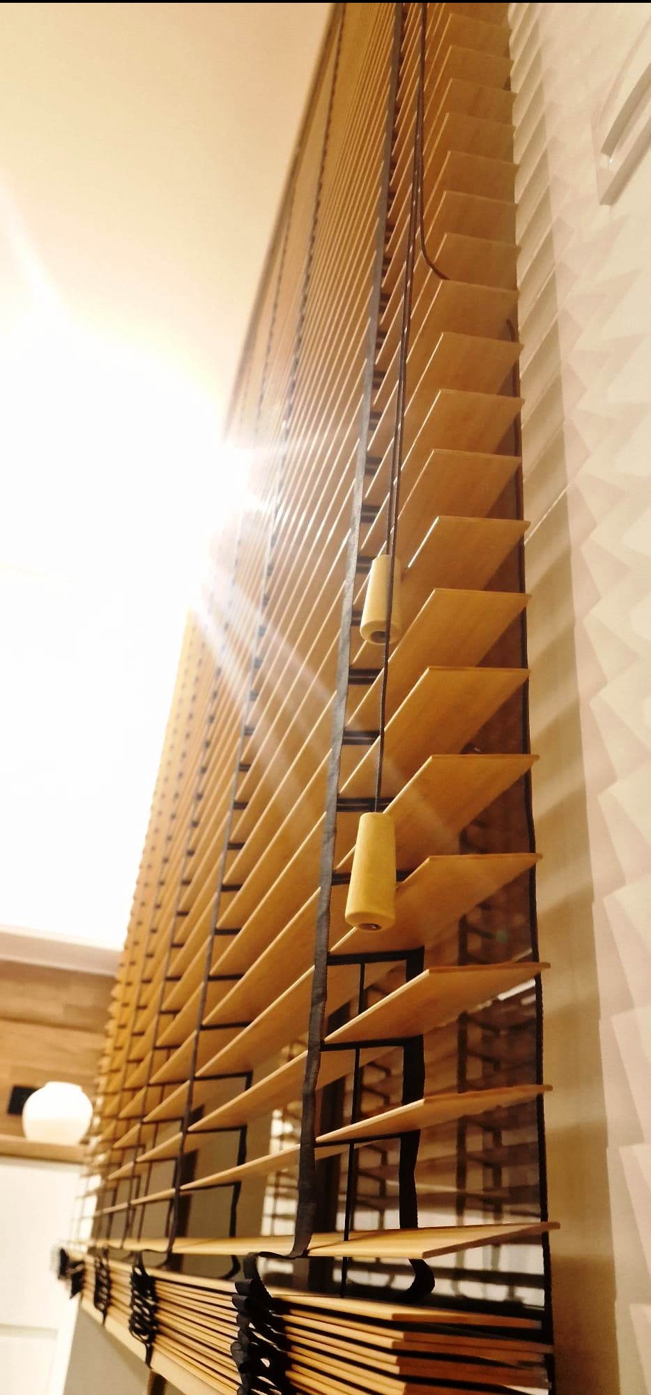 Bambusowe żaluzje poziome z czarną ramą, widok z dołu, z delikatnym światłem słonecznym. Naturalne drewno i nowoczesny design.