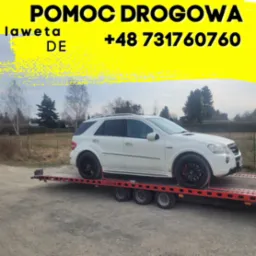 Biały SUV marki Mercedes-Benz ML na czerwonej platformie pomocy drogowej z żółtym tłem zawierającym tekst 'POMOC DROGOWA laweta DE +48 731760760'.