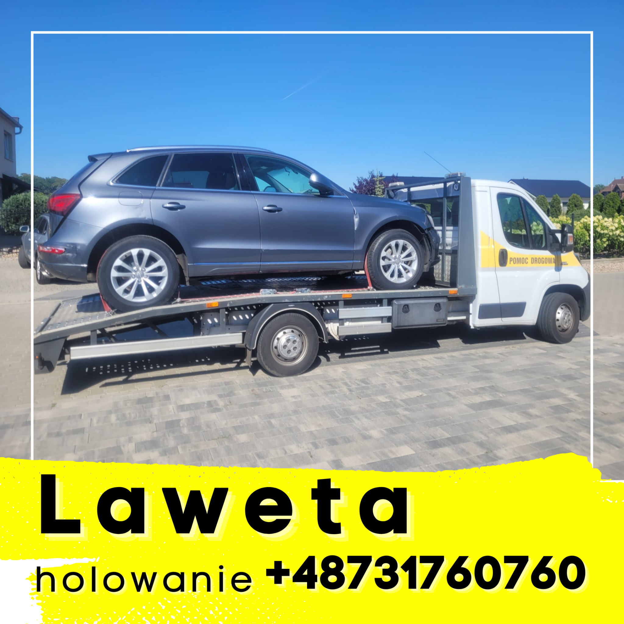 Szary samochód osobowy marki Audi Q5 na platformie białej lawety z żółtymi pasami, w tle domy jednorodzinne i błękitne niebo.