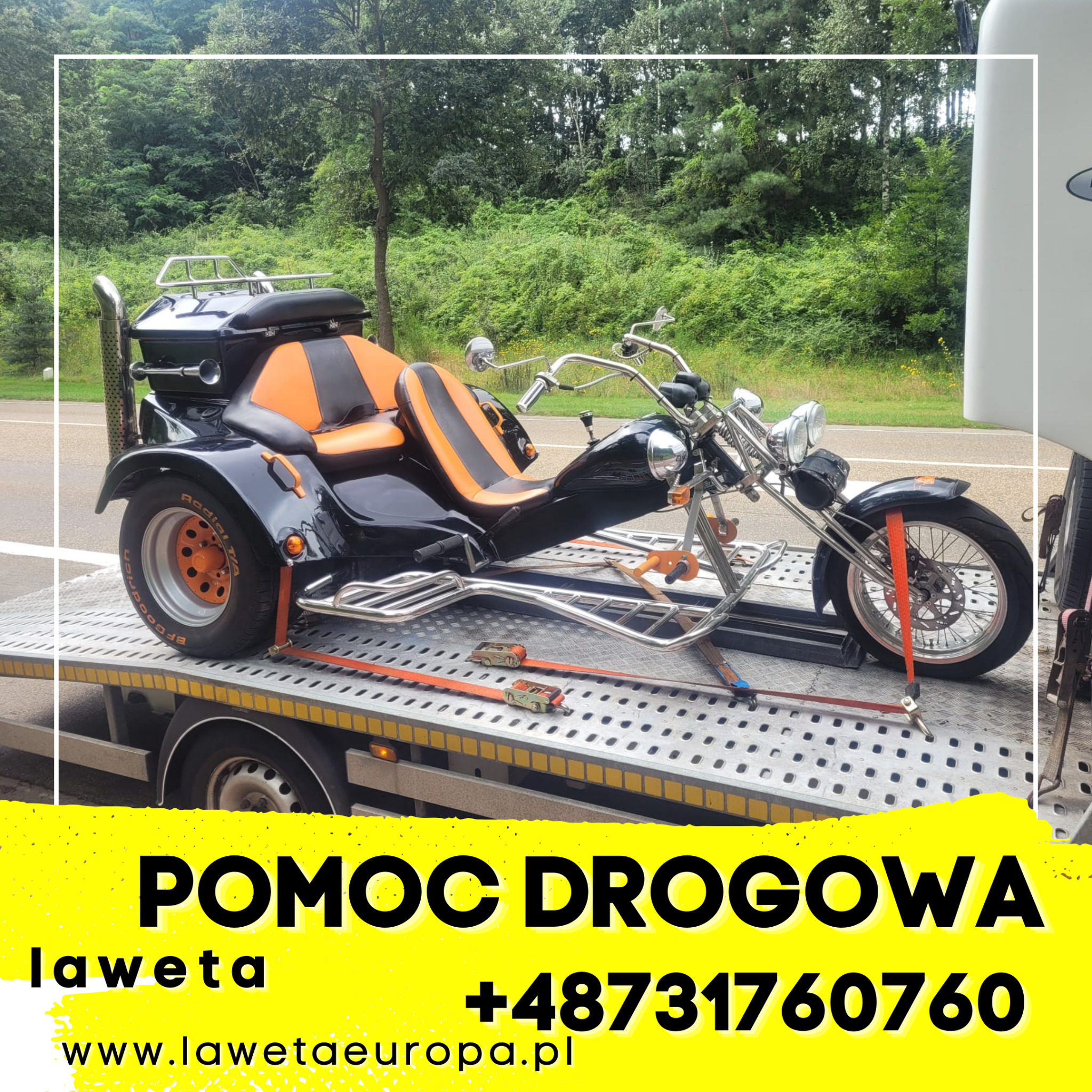 Czarny trójkołowy motocykl z pomarańczowymi siedzeniami zabezpieczony pasami na platformie lawety, widok z boku na tle zieleni.