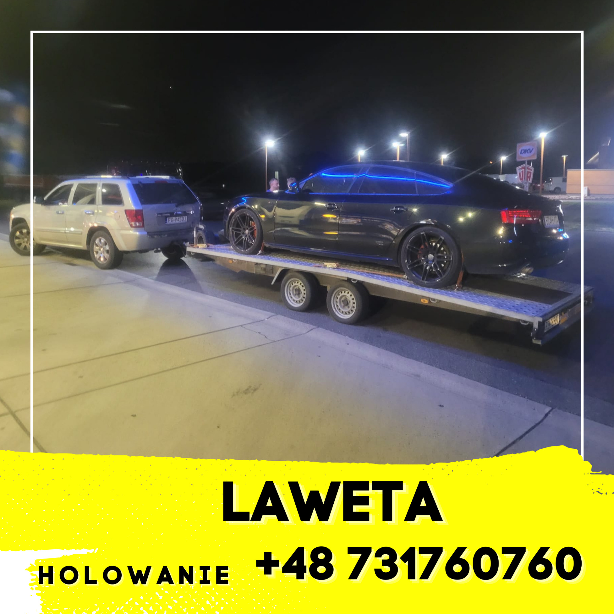 Czarny sportowy samochód z niebieskim oświetleniem LED na lawecie, holowany przez srebrnego SUV-a na parkingu oświetlonym latarniami.