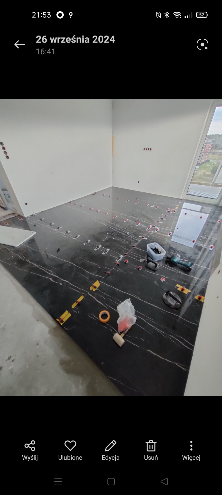 Układanie czarnych płytek z białym wzorem w Łopusznej. Widoczne narzędzia glazurnicze i system poziomowania. Podłoga w trakcie realizacji.