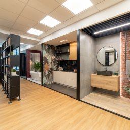 PRIMATER SPÓŁKA Z OGRANICZONĄ ODPOWIEDZIALNOŚCIĄ - Wnętrze biura z ekspozycją aranżacji łazienek i kuchni, prezentujące różne style wykończenia, od nowoczesnego minimalizmu po rustykalny z elementami cegły i naturalnych materiałów.