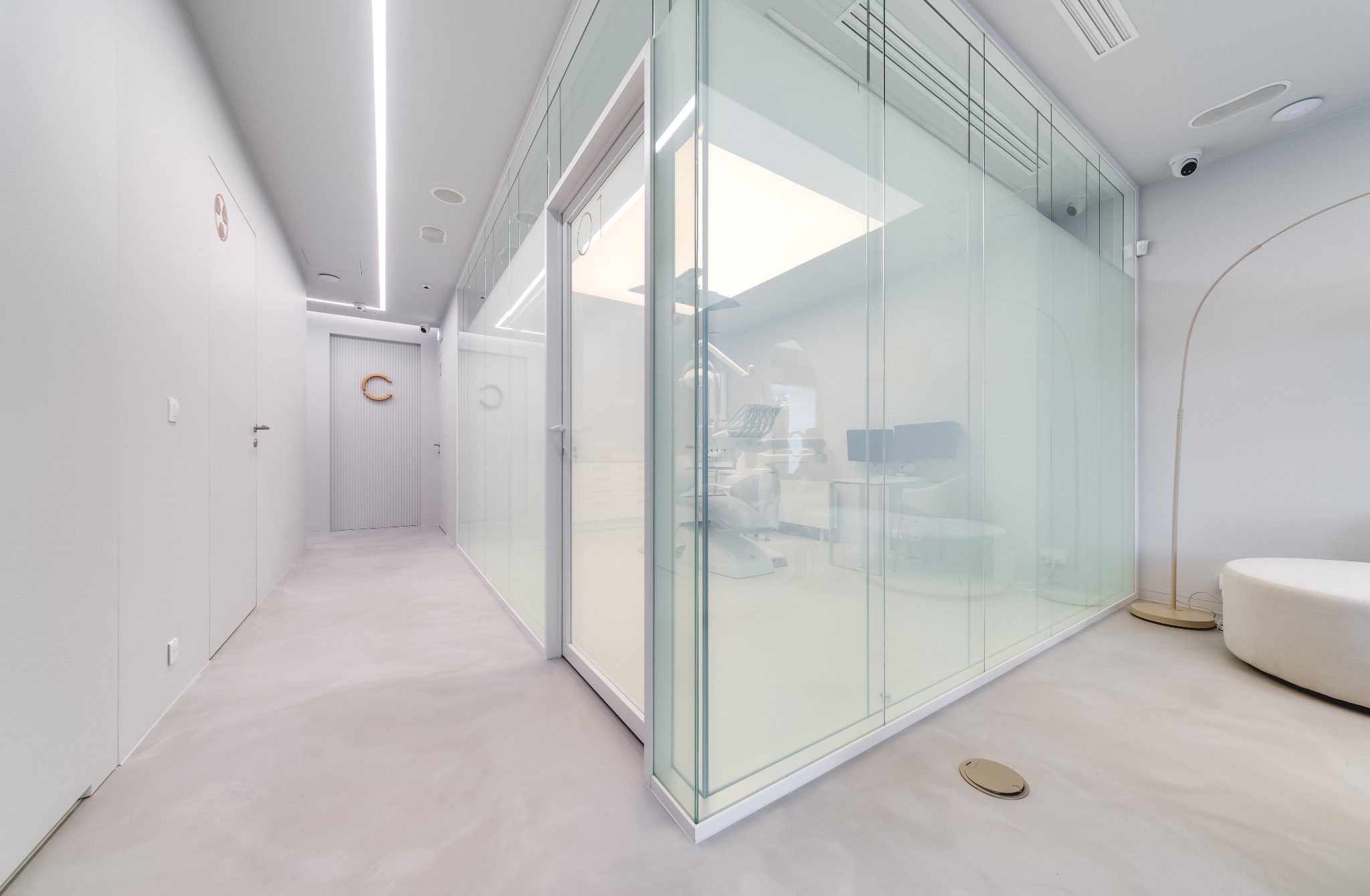 Minimalistyczne wnętrze biura stomatologicznego z przeszklonymi ścianami, widoczny sprzęt dentystyczny i oświetlenie LED.