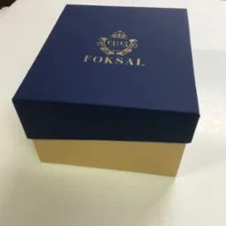 Eleganckie, dwuczęściowe pudełko w kolorze granatowym i beżowym z nadrukowanym złotym logo firmy FOKSAL, wykonane w Tychach. Widoczna faktura papieru.