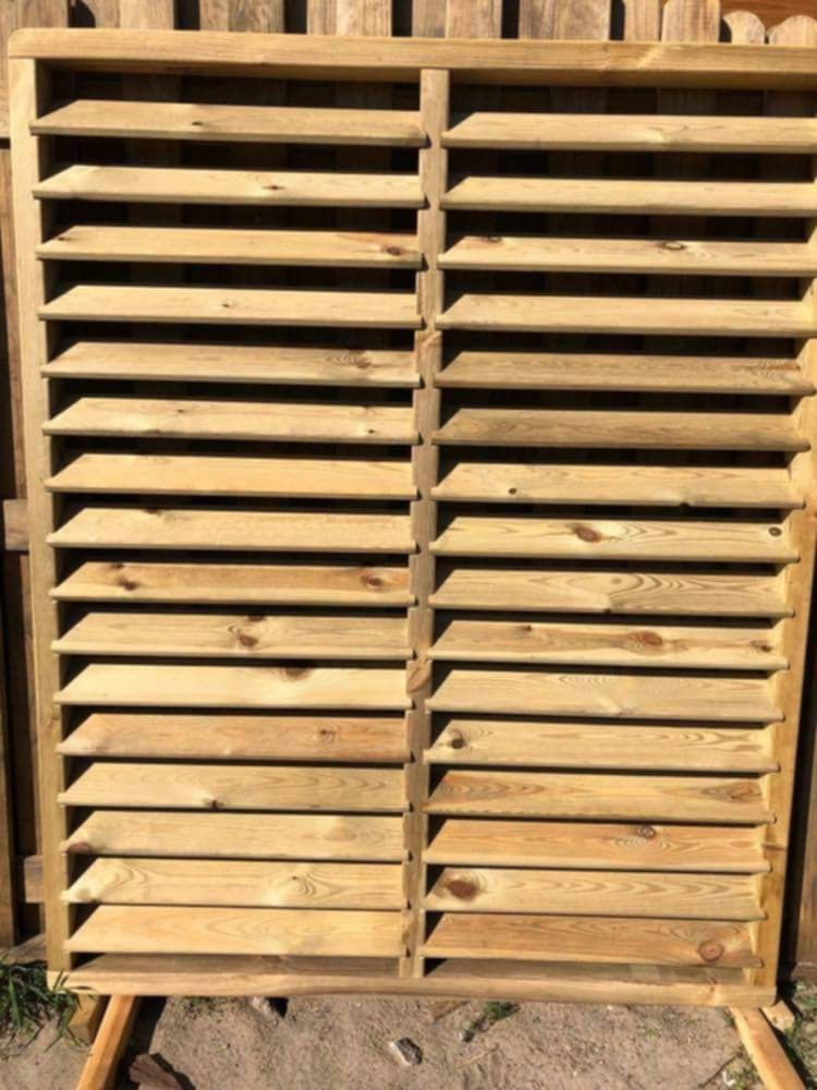 Drewniana konstrukcja z poziomymi lamelami, prawdopodobnie element ogrodzenia lub przesłony, w surowym stanie przed impregnacją, widoczne sęki i naturalny rysunek drewna.