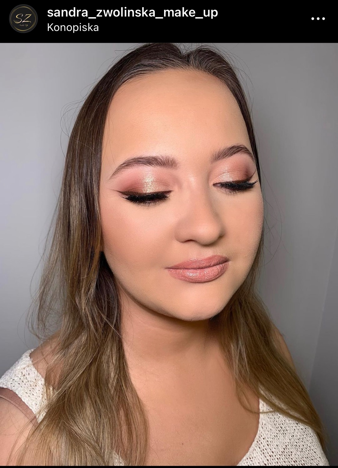 Portret kobiety z zamkniętymi oczami, prezentujący delikatny, błyszczący makijaż oka w odcieniach różu i złota, precyzyjną czarną kreskę oraz subtelny makijaż ust w odcieniu nude.