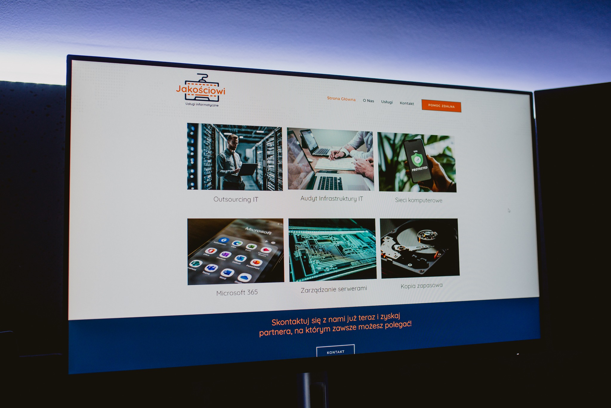 Ekran monitora wyświetlający stronę internetową firmy Jakosciowi z ofertą usług informatycznych, w tym Outsourcing IT, Audyt Infrastruktury IT, Sieci komputerowe, Microsoft 365, Zarządzanie...