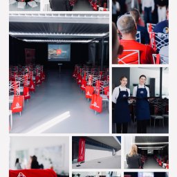 Sandra Marcinkowska - Przygotowania do konferencji: sala z rzędami krzeseł z czerwonymi torbami z logo firmy, kelnerki z tacami, ustawione stoły z czarnymi obrusami, prezentacja na ekranie.