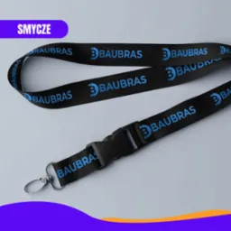 Czarny smycz z niebieskim nadrukiem logo firmy 'Baubras' na szarym tle, z metalowym karabińczykiem i plastikową klamrą.