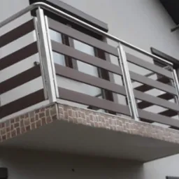 Balkon z balustradą ze stali nierdzewnej z poziomymi, brązowymi panelami, wykończony płytkami imitującymi cegłę, widok z dołu.