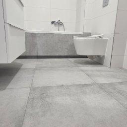 GÓRECKI BUDOWNICTWO Dominik Górecki - Nowoczesna łazienka z szarą podłogą z płytek, wiszącą toaletą i białą szafką pod umywalką. Minimalistyczny design, świeżo po remoncie.