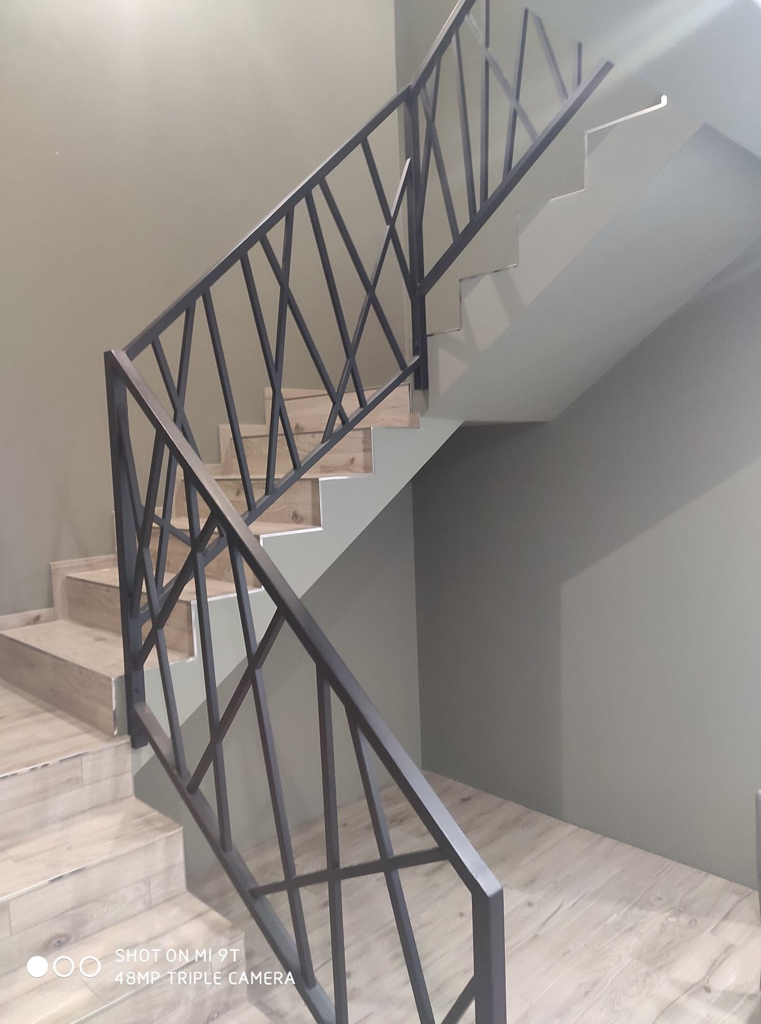 Schody z drewnopodobnymi płytkami i nowoczesną, geometryczną, czarną balustradą metalową w Lubartowie.