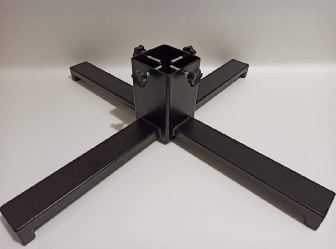 Metalowa podstawa krzyżowa z czterema ramionami, czarne wykończenie, widoczne śruby regulacyjne, na jednolitym jasnym tle.