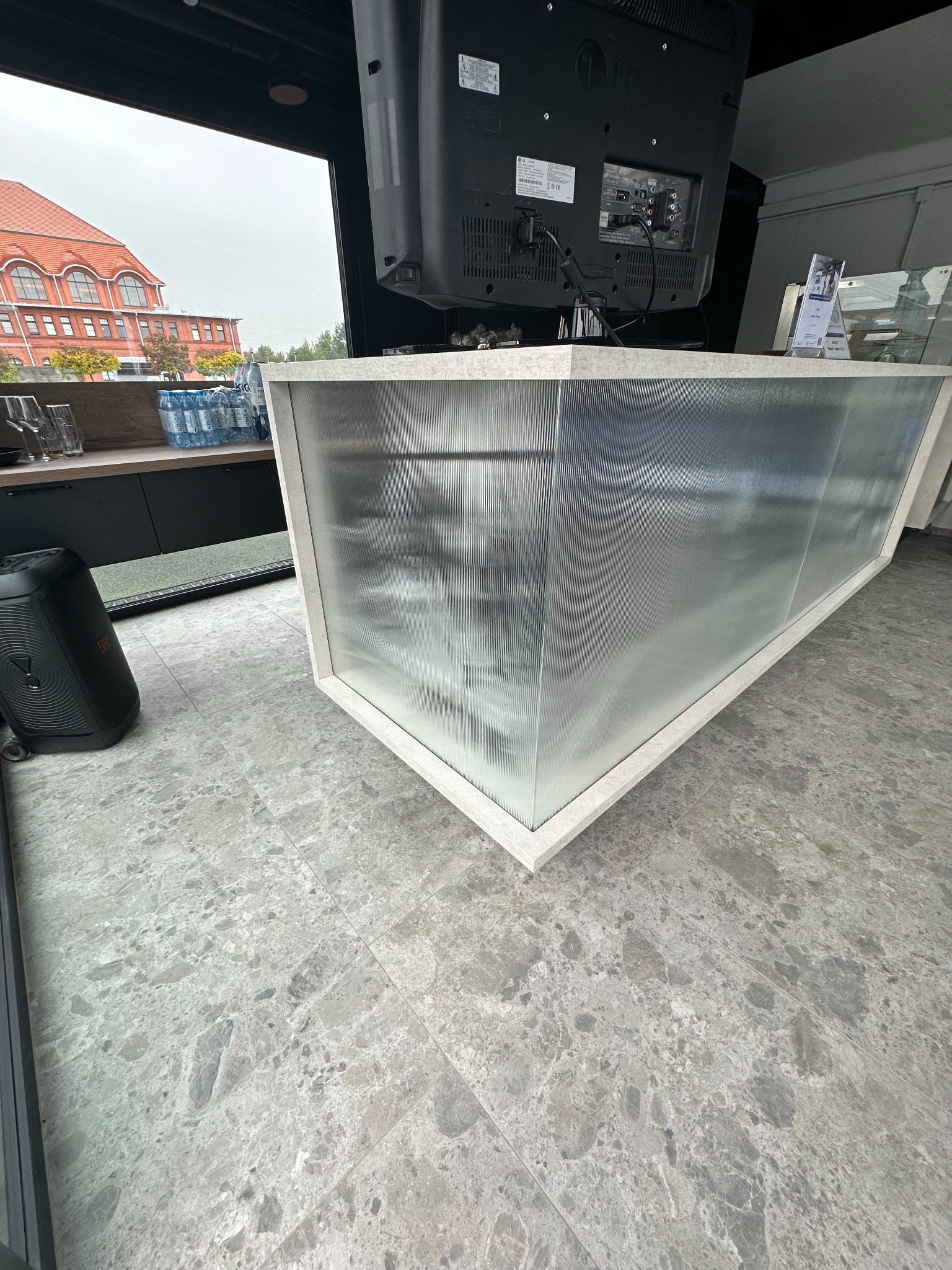 Nowoczesna zabudowa meblowa z ryflowanego szkła, widok z dołu, widoczny fragment budynku z czerwonej cegły za oknem.