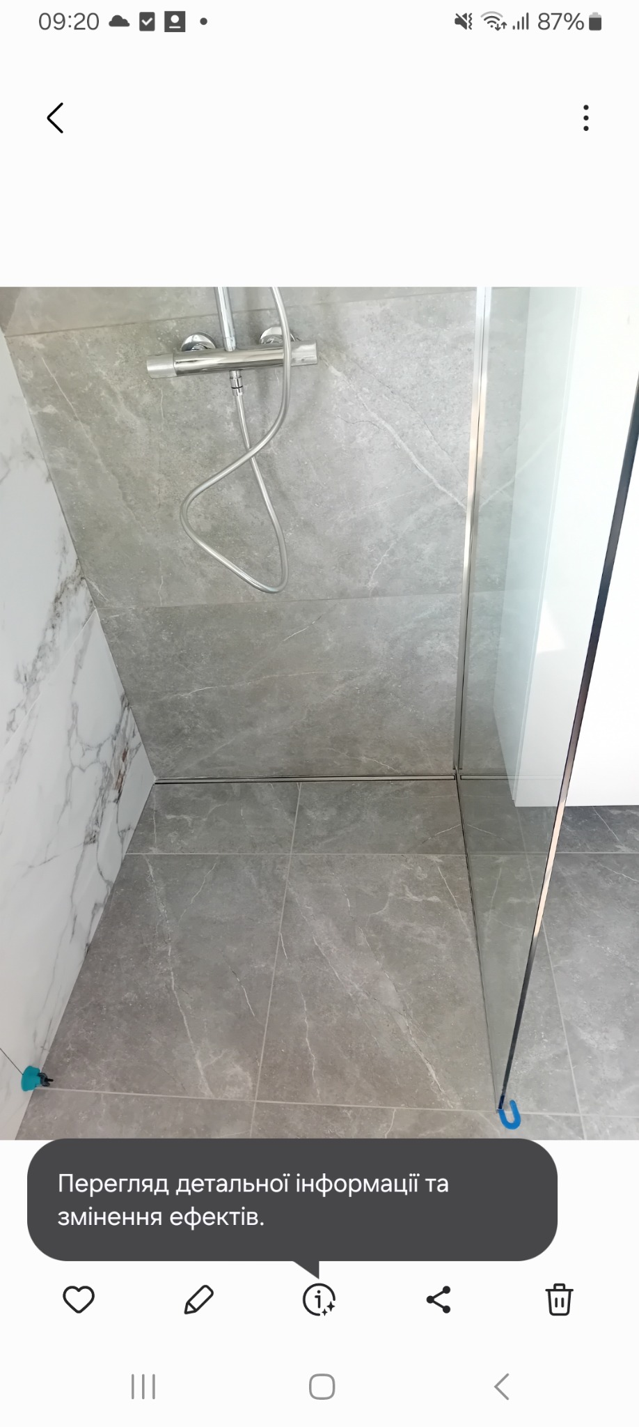 Wykończona kabina prysznicowa z szarymi płytkami imitującymi marmur na ścianach i podłodze, widoczny chromowany zestaw prysznicowy i szklana ściana kabiny z metalowymi profilami.