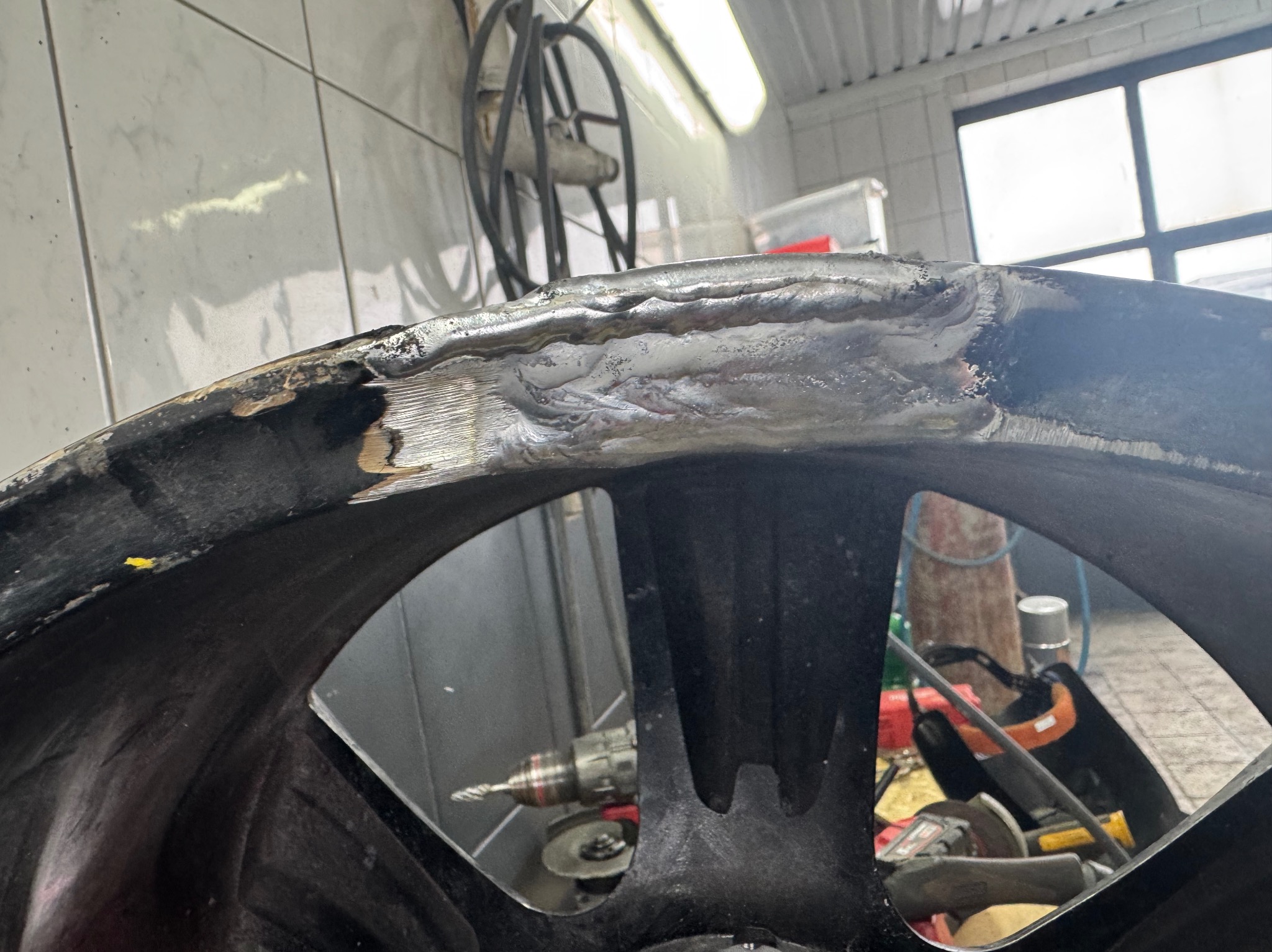 Naprawa felgi aluminiowej po spawaniu w warsztacie w Gdańsku. Widoczne ślady obróbki i narzędzia.