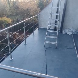 J-B.R.W Jakub Wasila - Wykończony balkon z szarą podłogą i metalową balustradą. Widoczne narzędzia i drabina. W tle zieleń drzew. Ujęcie z góry.
