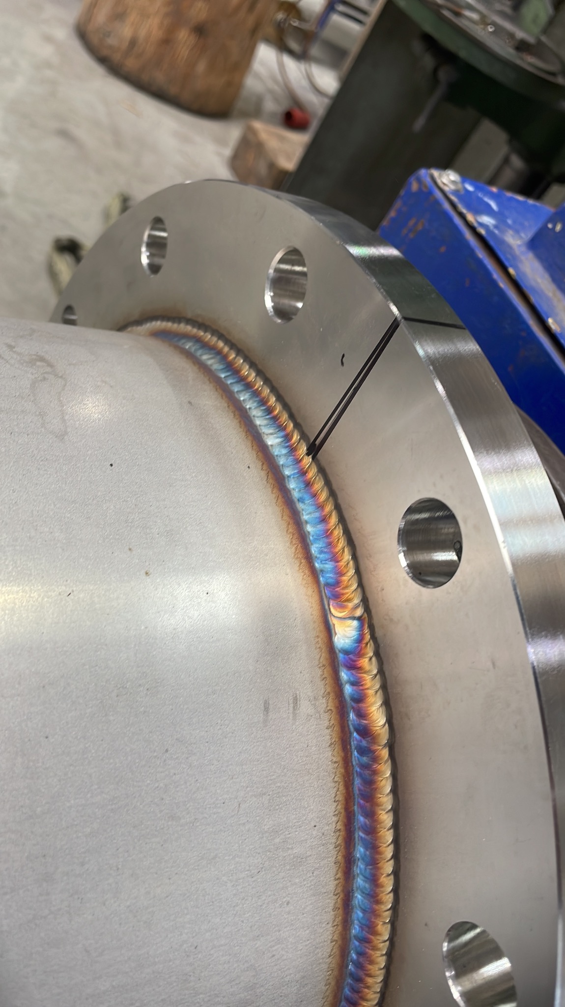 Zbliżenie na spoinę łączącą rurę ze stalowym kołnierzem, widoczne charakterystyczne przebarwienia termiczne