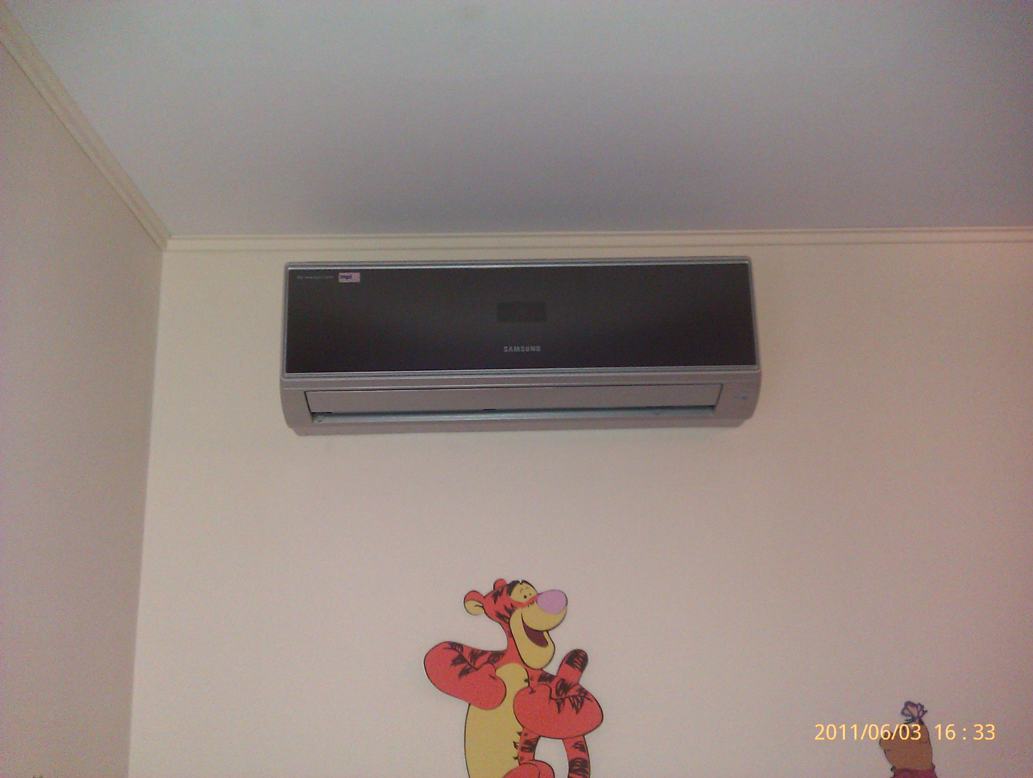Zamontowany na ścianie klimatyzator marki Samsung w pokoju dziecięcym z naklejką Tygryska z Kubusia Puchatka.