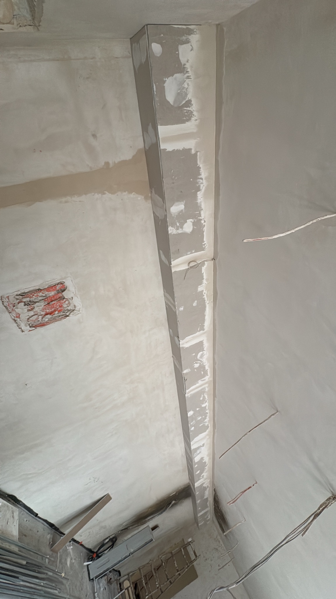 Sufit po szpachlowaniu, z widocznym profilem i śladami po gładzi. Widoczne kable i narzędzia. Ujęcie z dołu, sufit w odcieniach bieli i szarości.