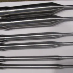 Sześć precyzyjnie obrobionych, metalowych prętów o różnej grubości i kształcie, ułożonych równolegle na białym tle, z widocznymi śladami obróbki.