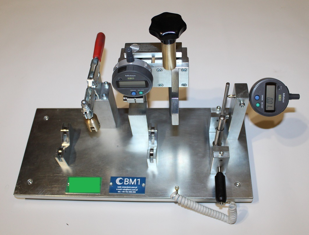 Precyzyjny przyrząd pomiarowy z dwoma cyfrowymi wskaźnikami Mitutoyo, uchwytem szybkomocującym i elementami regulacyjnymi na metalowej podstawie.