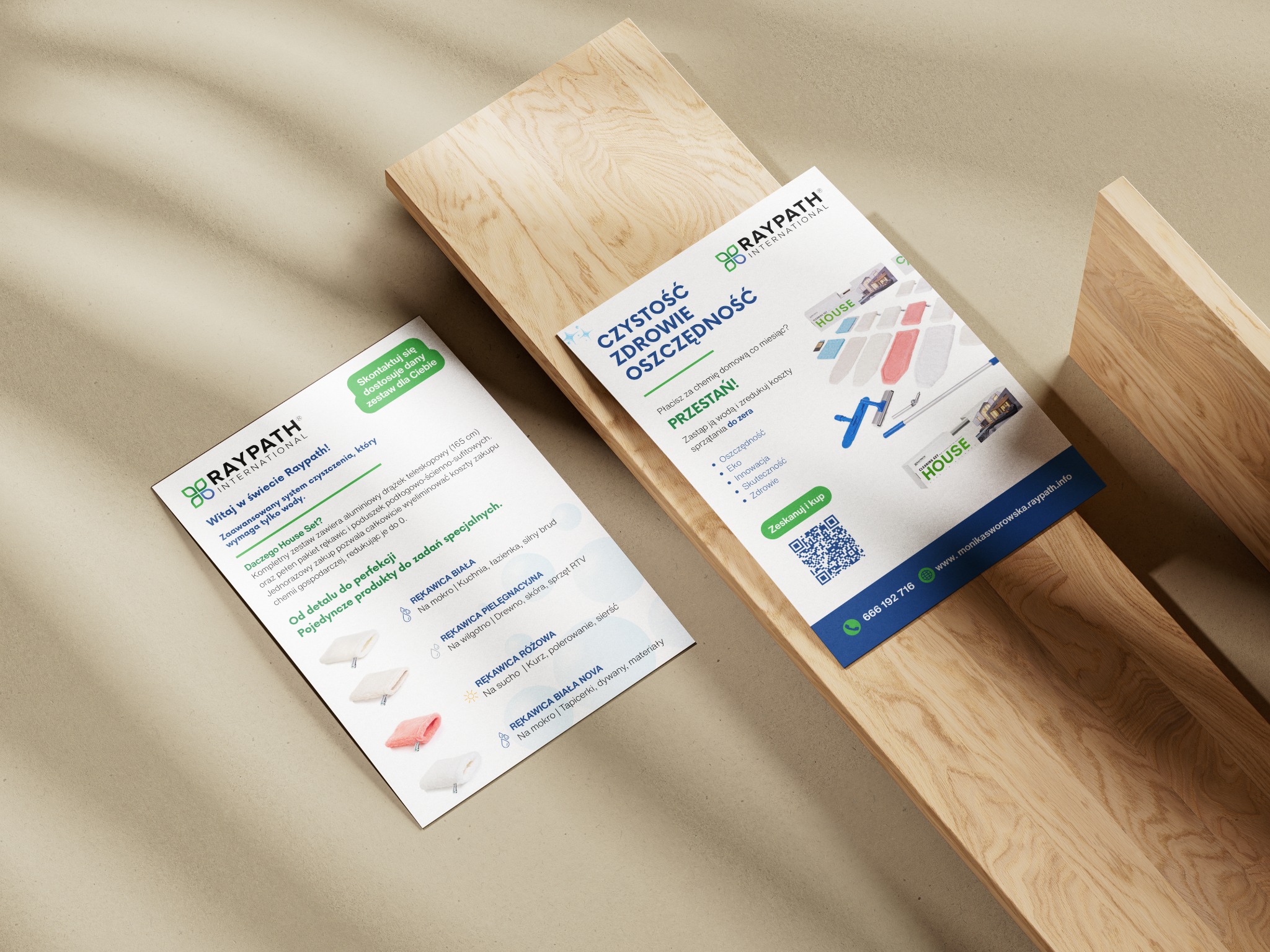Dwie ulotki informacyjne Raypath International leżące na drewnianym blacie. Ulotki prezentują produkty do czyszczenia bez użycia chemii, z QR kodem i danymi kontaktowymi.