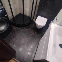 Prywatnie - Nowoczesna łazienka z czarną kabiną prysznicową, marmurową podłogą, białą umywalką z szafką i toaletą, oraz pralką.