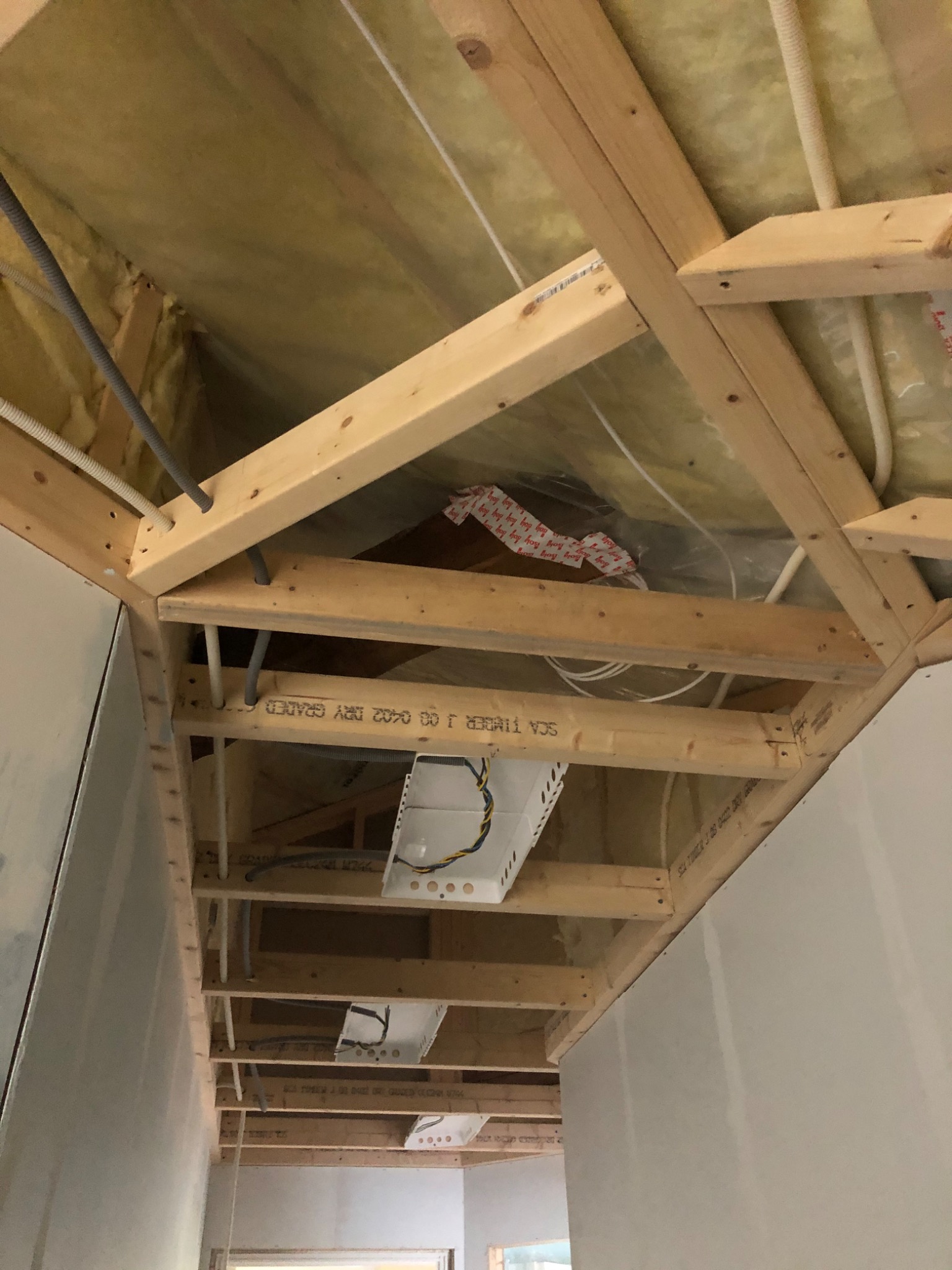 Konstrukcja drewniana sufitu podwieszanego z ociepleniem wełną mineralną, widoczne kable elektryczne i puszki instalacyjne przed montażem płyt.