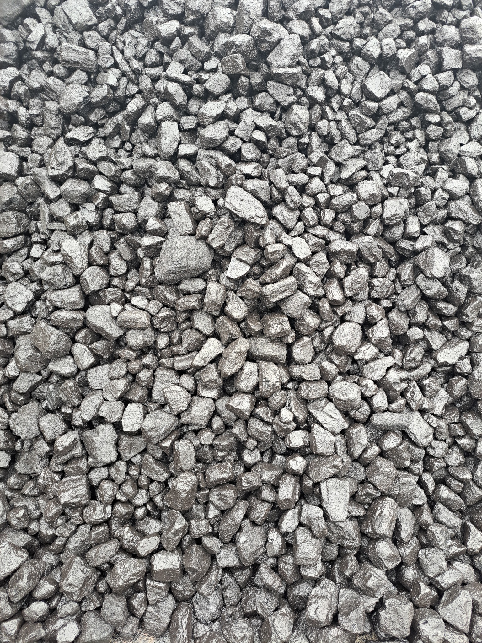 Góra antracytowych bryłek węgla, z widocznymi krawędziami i refleksami światła