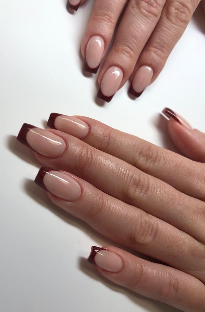 Eleganckie, beżowe paznokcie z ciemnobrązowym french manicure, kwadratowy kształt, widoczne detale skóry dłoni.