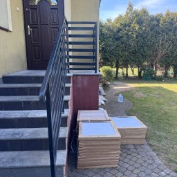 professional mobile welder PMWelders - Nowoczesna balustrada schodowa z czarnych, prostych profili, widok na wejście do domu i stosy płytek na posesji.