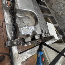 professional mobile welder PMWelders - Spawanie elementu metalowego z widocznym spawem i uchwytem spawalniczym WP26 na warsztatowym stole. Obróbka metalu w trakcie realizacji.