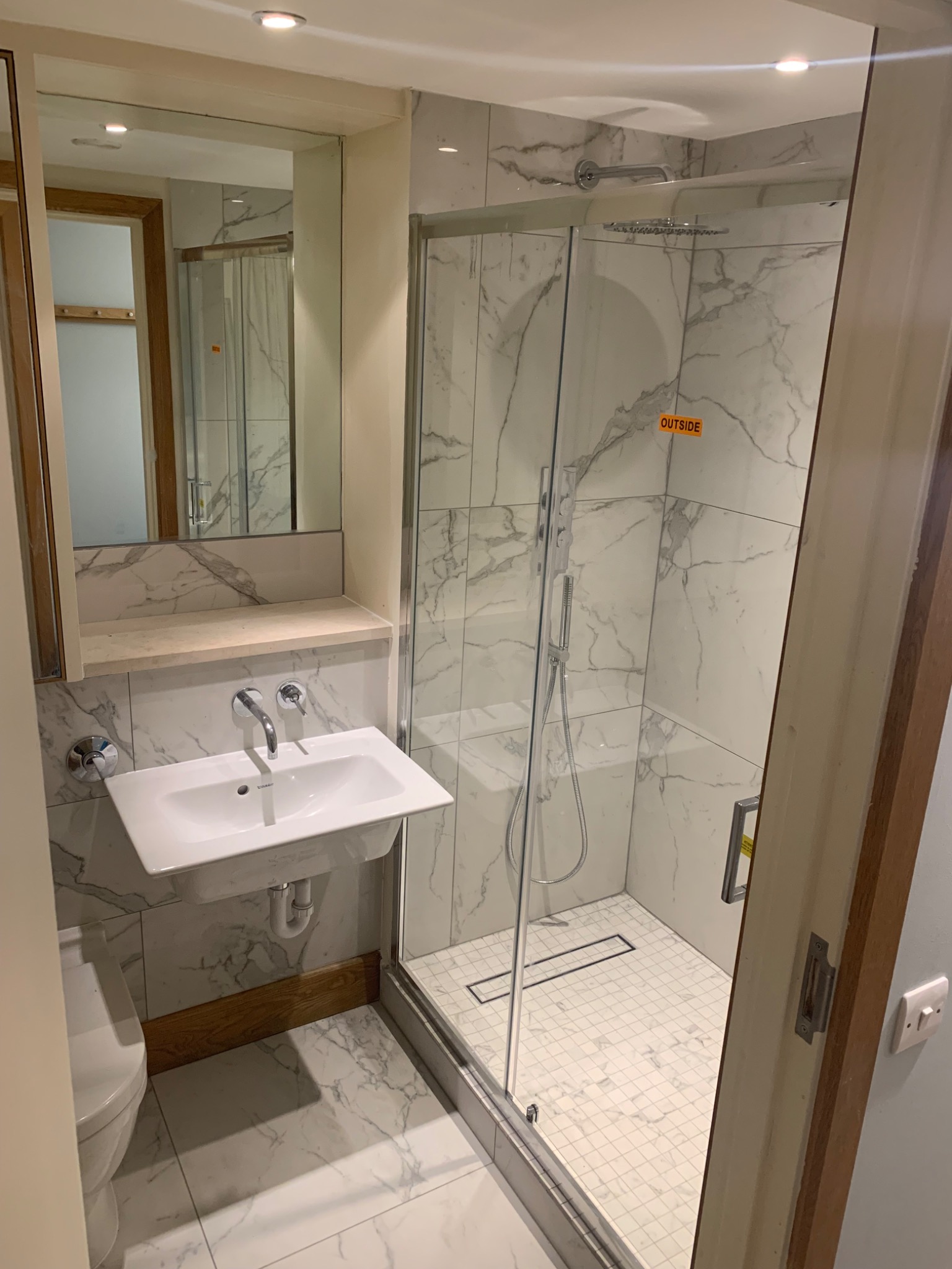 Nowoczesna łazienka w Domaradzu z kabiną prysznicową typu walk-in wykończoną marmurową płytką, umywalką nablatową i dużym lustrem.