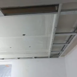 Stelaż metalowy podwieszanego sufitu z płyt gipsowo-kartonowych, widoczne otwory na oświetlenie punktowe, stan surowy przed wykończeniem.