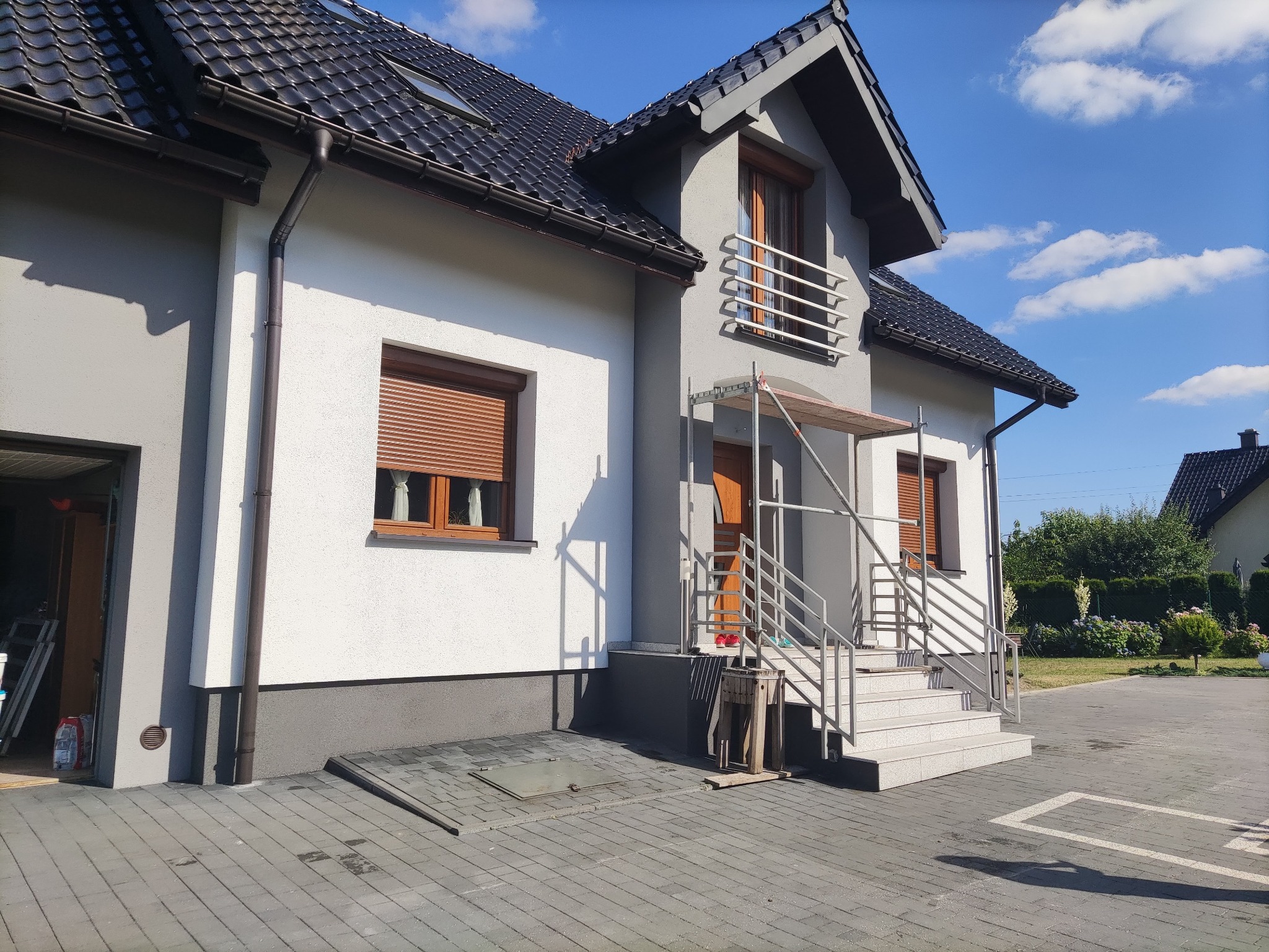 Dom jednorodzinny po częściowym odświeżeniu elewacji w Żorach, widoczne rusztowanie przy wejściu i świeżo pomalowane fragmenty ścian.