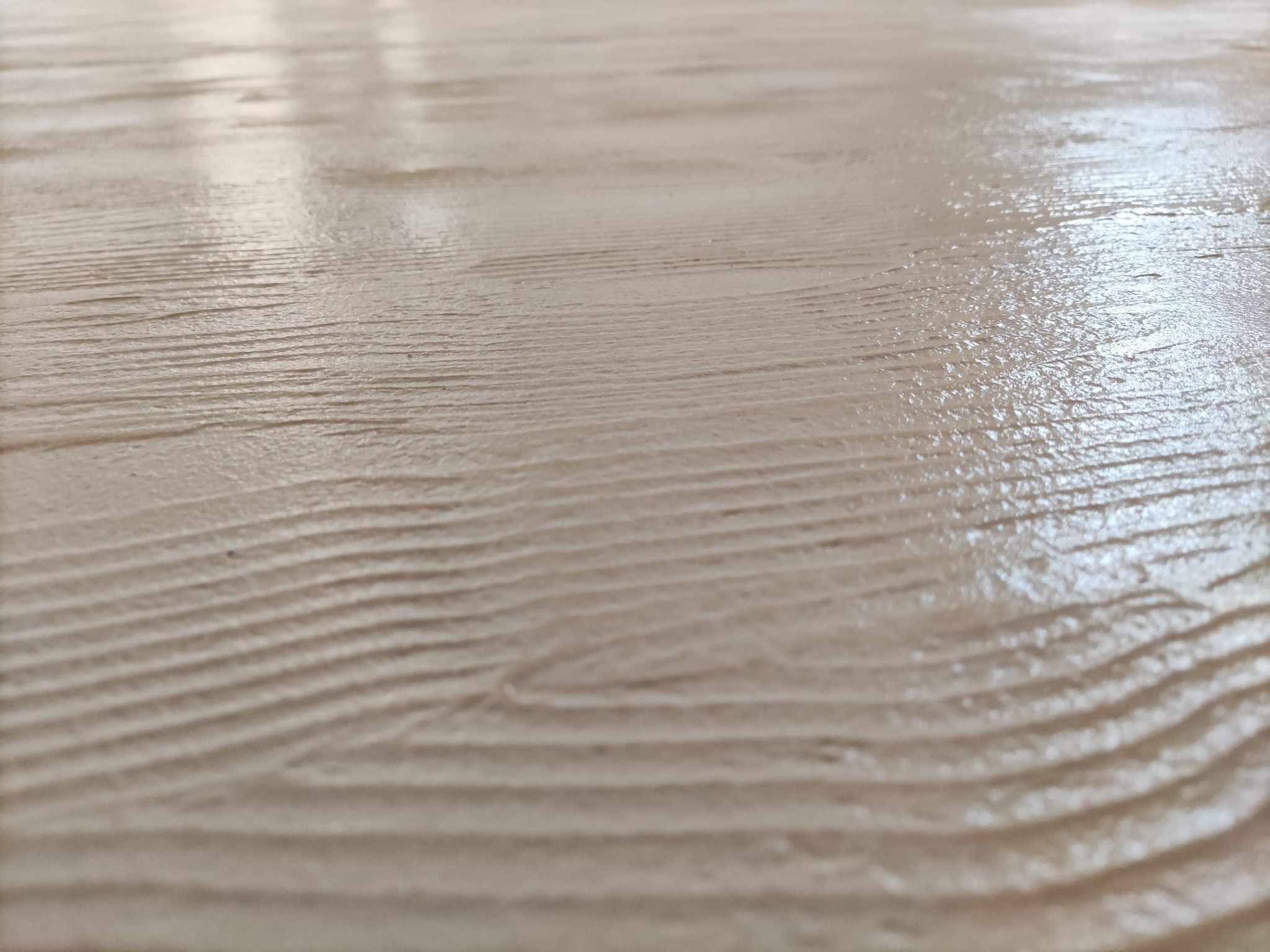 Szczegółowe ujęcie świeżo pomalowanej powierzchni z wyraźną fakturą drewna i delikatnym połyskiem, imitującą naturalne usłojenie.