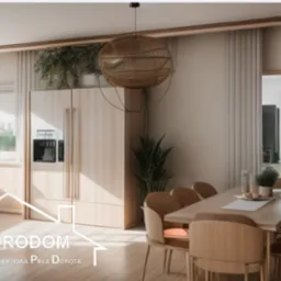 Jasna, przestronna kuchnia z jadalnią w stylu skandynawskim, z drewnianymi meblami, okrągłym lampionem nad stołem i roślinami doniczkowymi, widoczny logotyp firmy projektowej w dolnej części zdjęcia.