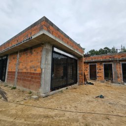 MK Fenster - Maciej Kaszczyk @oknamaciek - Montaż żaluzji fasadowych na surowej elewacji budynku z cegły, widoczne narzędzia i drabina.