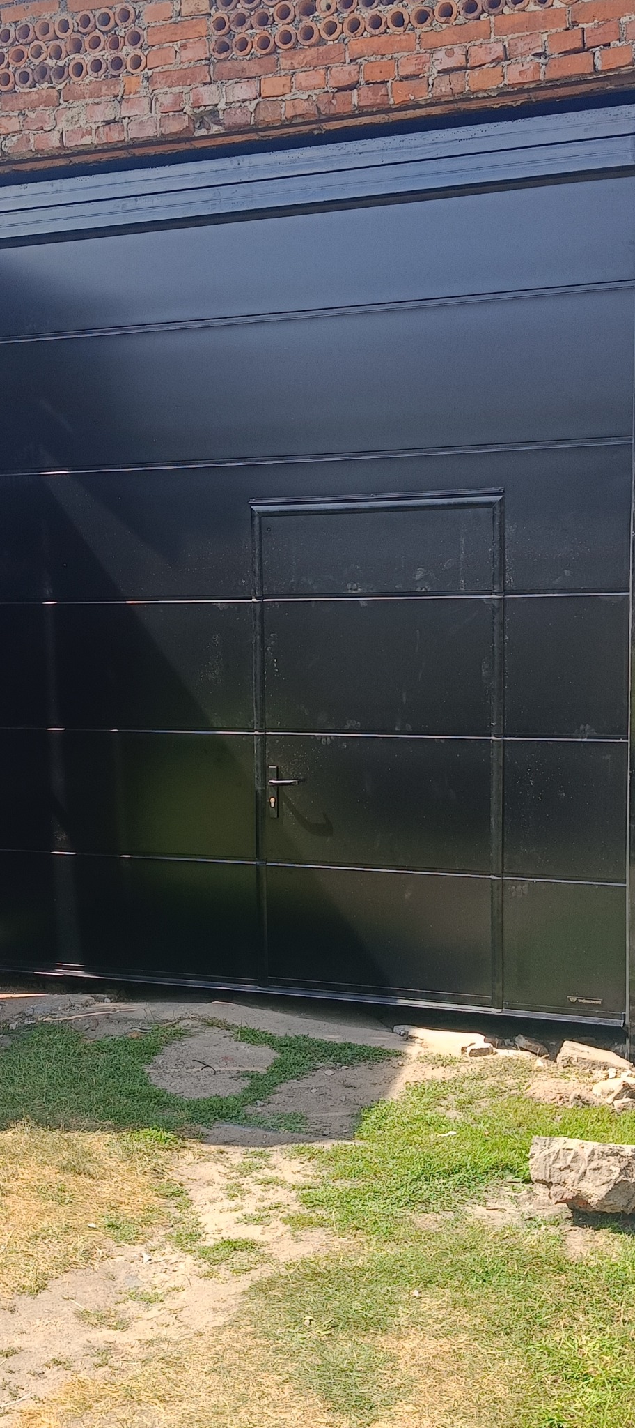 Brama segmentowa z niesymetryczna furtka w czarnym kolorze