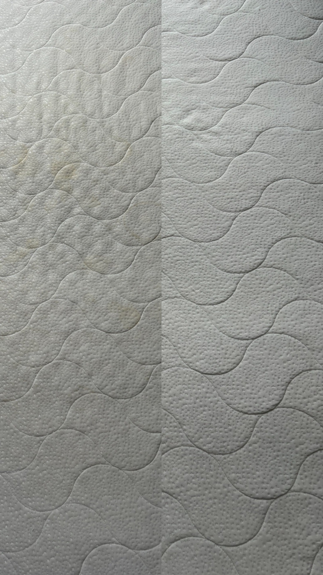 Fragment materaca z widocznym podziałem na część wyczyszczoną i zabrudzoną, ukazujący efekt przed i po czyszczeniu.