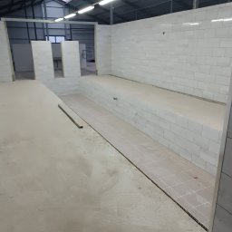 Piter HOME - Wnętrze w trakcie prac wykończeniowych: częściowo wyłożone płytki na ścianach i podłodze, surowy beton na posadzce, widoczne przygotowania do dalszych prac.