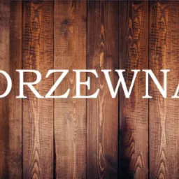 Ciemnobrązowe deski z wyraźnym usłojeniem, na których widnieje biały napis 'DRZEWNA' dużymi literami.