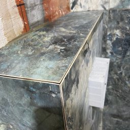 KVB CONSTRUCTION KAMIL VIP BUD Kamil Damps - Półka z płytek imitujących marmur w trakcie montażu w łazience, widoczne niedokończone ściany i biała kratka wentylacyjna.