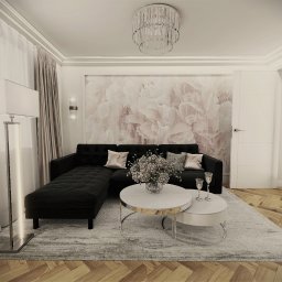 NAJ House Anna Najdek - Elegancki salon z czarną sofą modułową, dwoma okrągłymi stolikami kawowymi z marmurowymi blatami i srebrnymi nogami, bukietem kwiatów w wazonie, dwoma kieliszkami do wina, lampą podłogową...